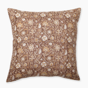 A square decorative pillow featuring a rich rust background adorned with intricate floral patterns in white and gold. The design includes various flowers and leaves, creating an elegant, sophisticated look. The edges of the pillow are clean and neatly finished.