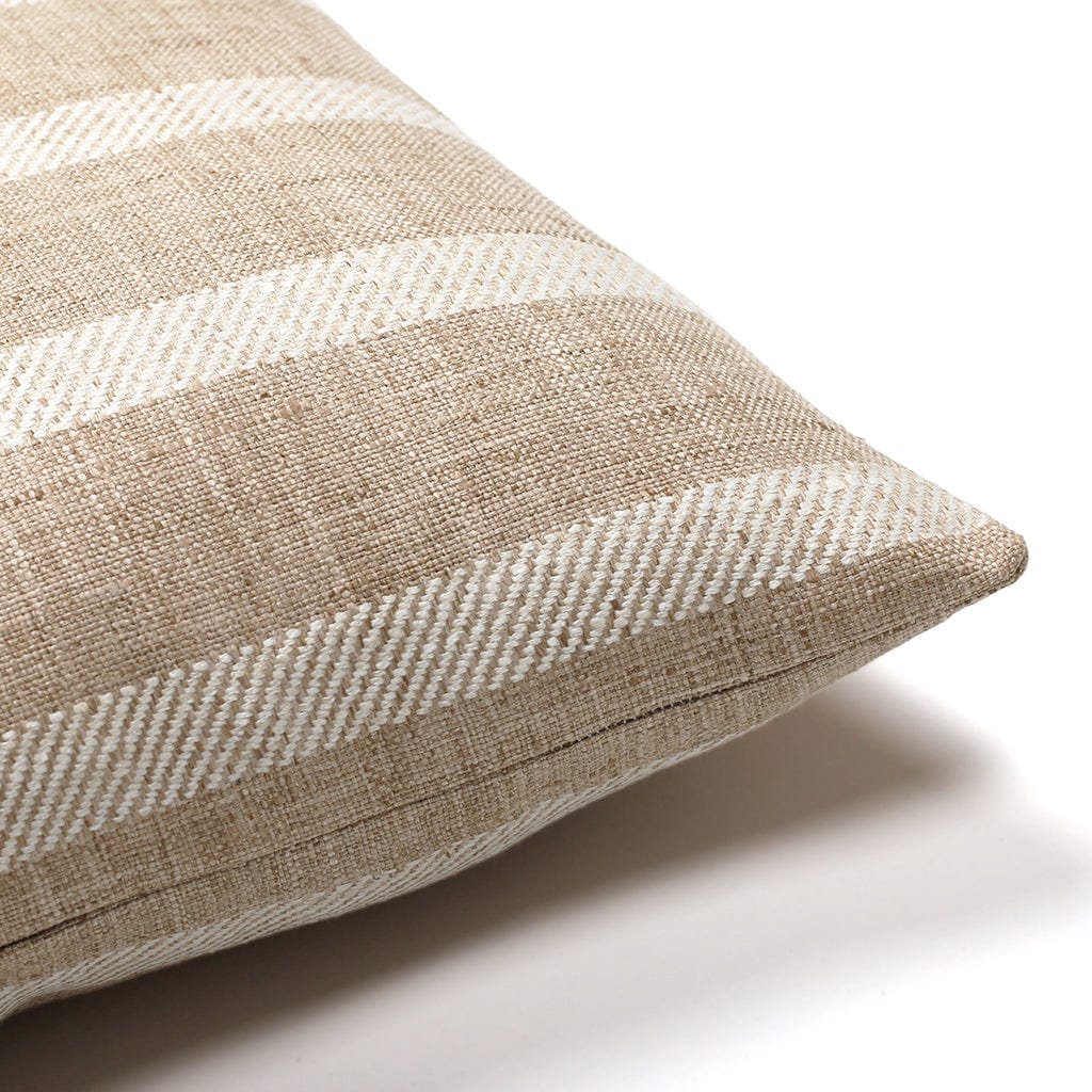 A close-up of a beige and white striped, woven throw pillow. The pillow has diagonal white lines and a textured fabric, lying on a white background.