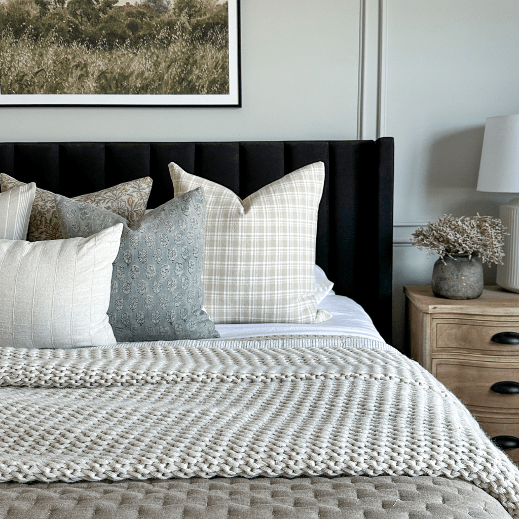 A close up of a bed with a black headboard and Copeland, Eloise, and Logan Lumbar from Colin + FInn