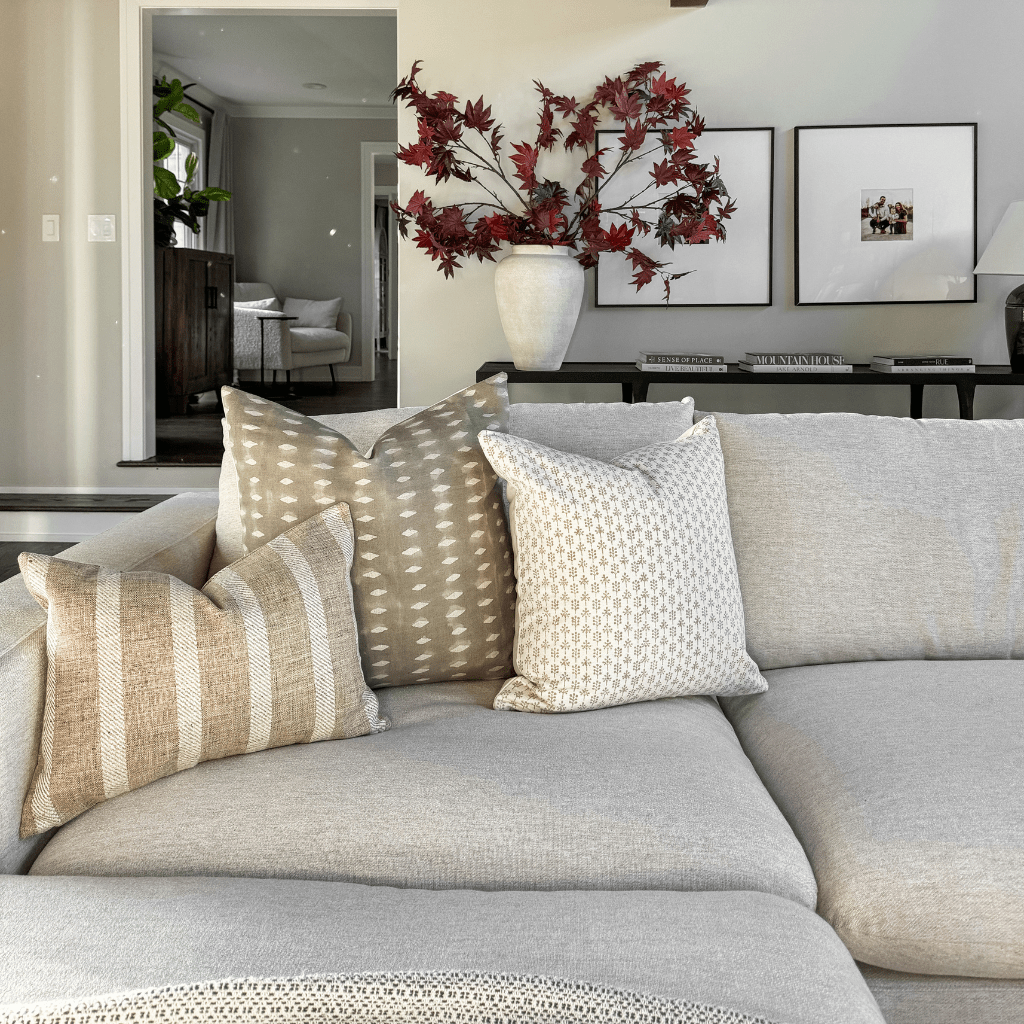 Henry pillow combination on a gray sofa with a rust floral arrangement in the background.