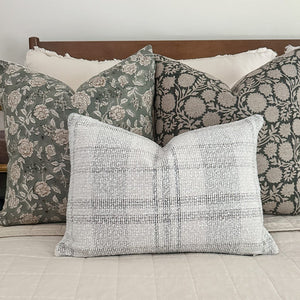 Lenora, Callum, and Tobias lumbar pillows set on a bed with a wooden headboard and white pillows behind them.