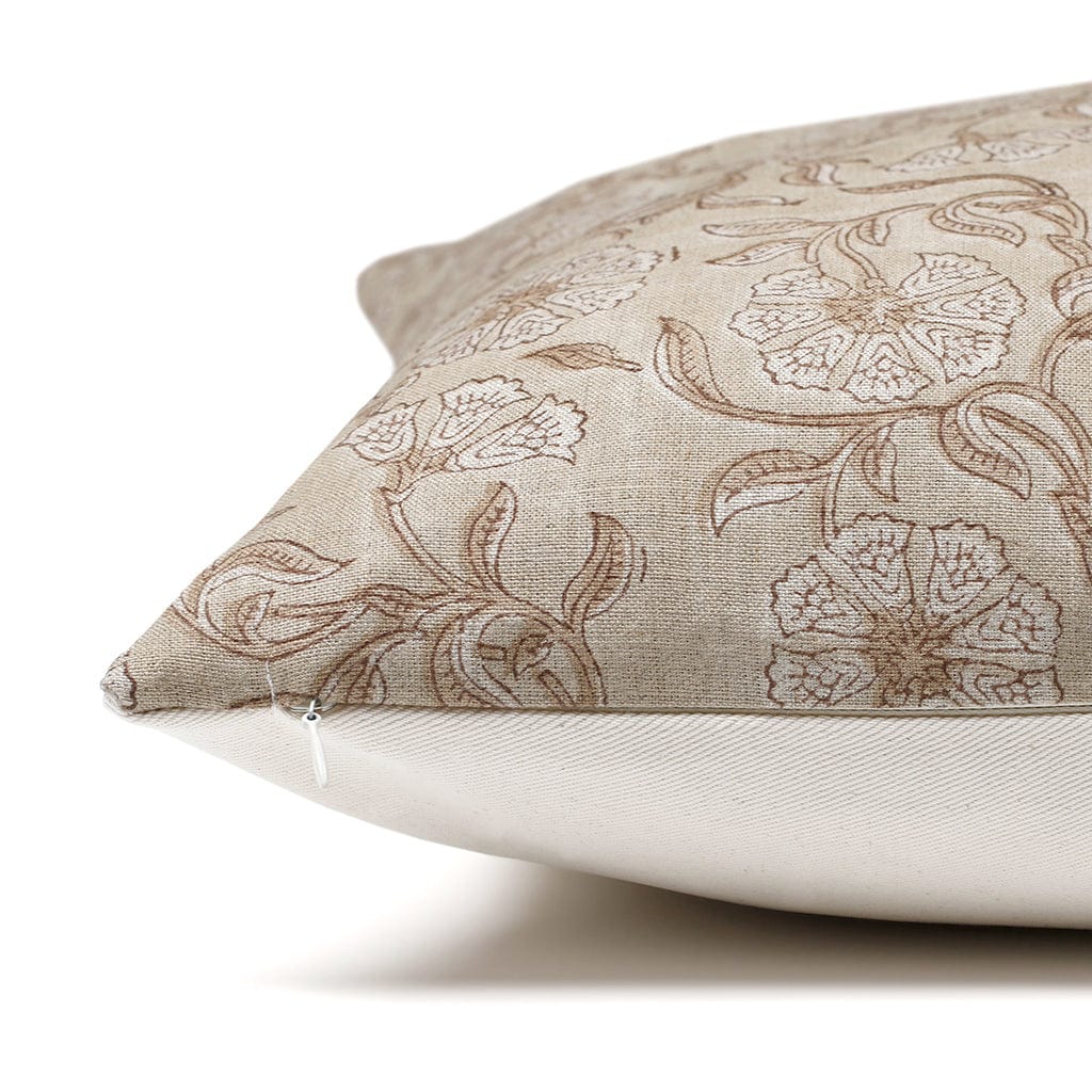 A close-up side view of a beige throw pillow with a floral pattern. The midsection of the pillow displays intricate brown flowers and leaves, with a visible zipper at one end. The corner of the pillow is prominently shown against a white background.