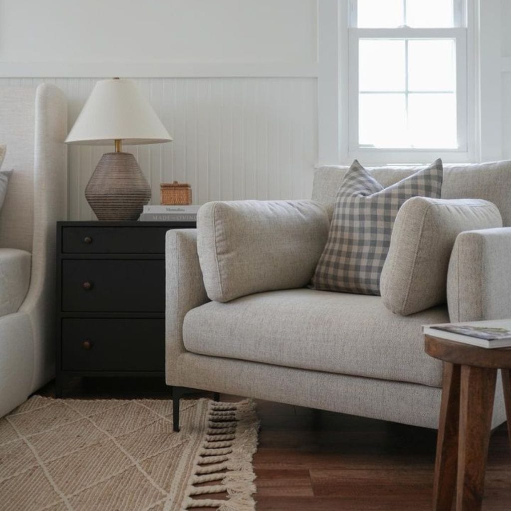 Maxwell pillow cover on a gray side chair. Bedroom with black nightstand and lamp.