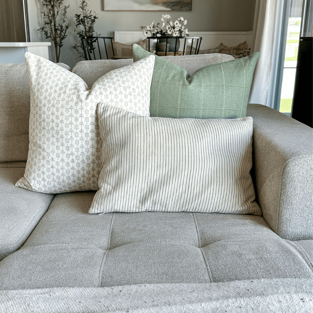 Odette, Allister, and Laney Lumbar in the corner of a grey sofa