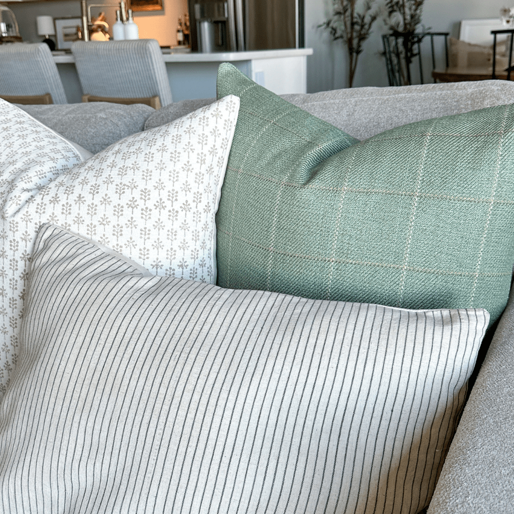 A close up of Odette, Allister, and Laney Lumbar in the corner of a grey sofa