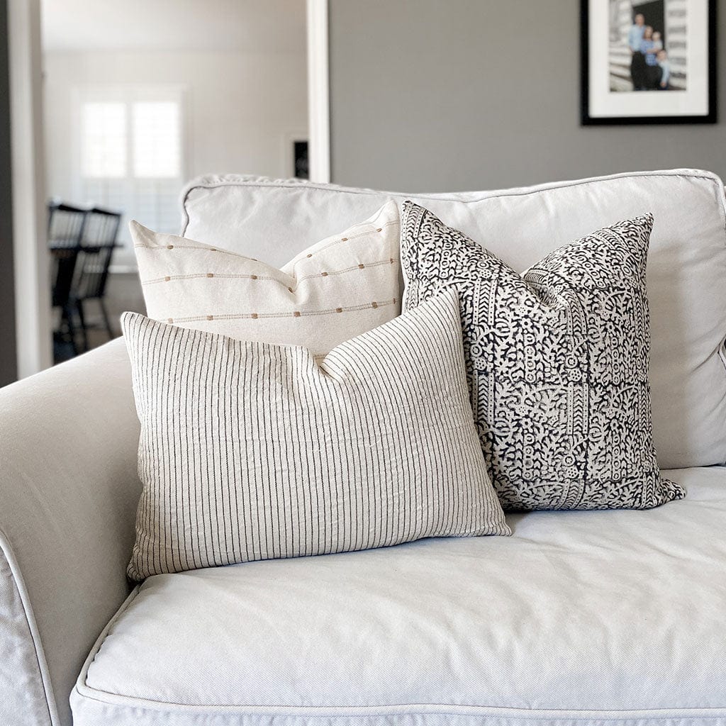 Greyson pillow combination from Colin and Finn on a white couch with kitchen and family photos blurred in the background.